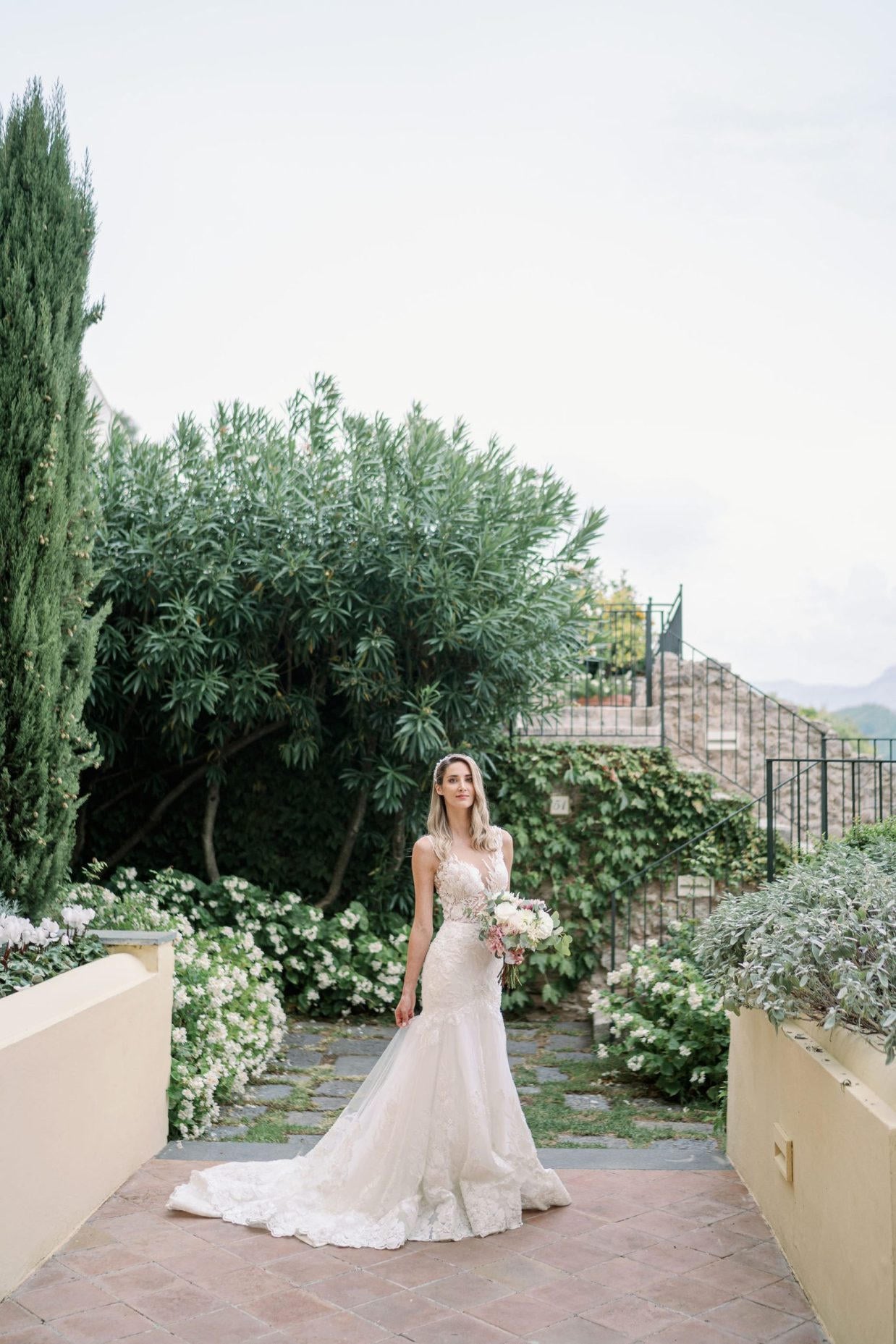 Bride in elegant lace wedding gown standing in a garden setting