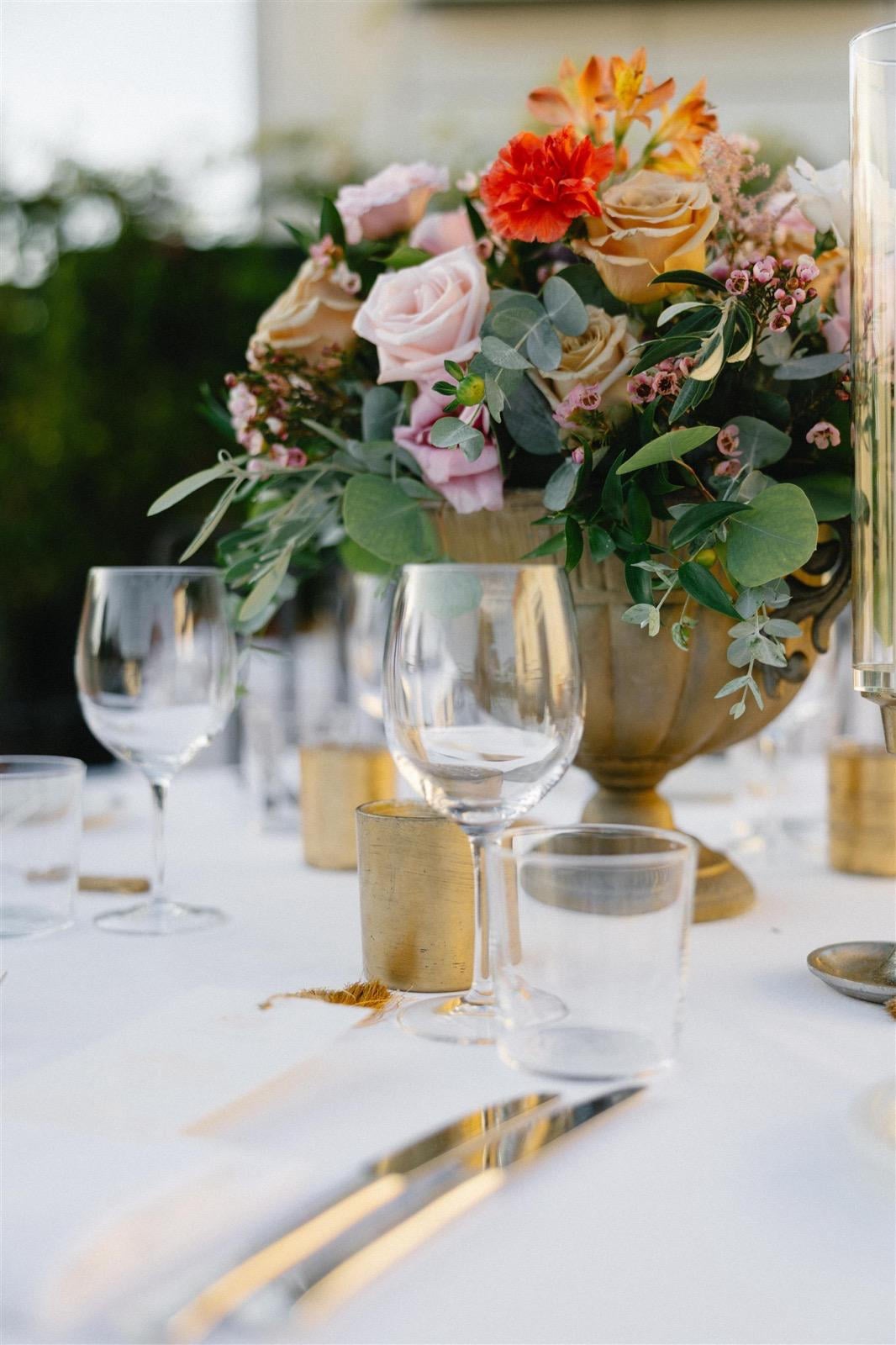 Elegant table setting with a floral arrangement, glassware, and golden candleholders