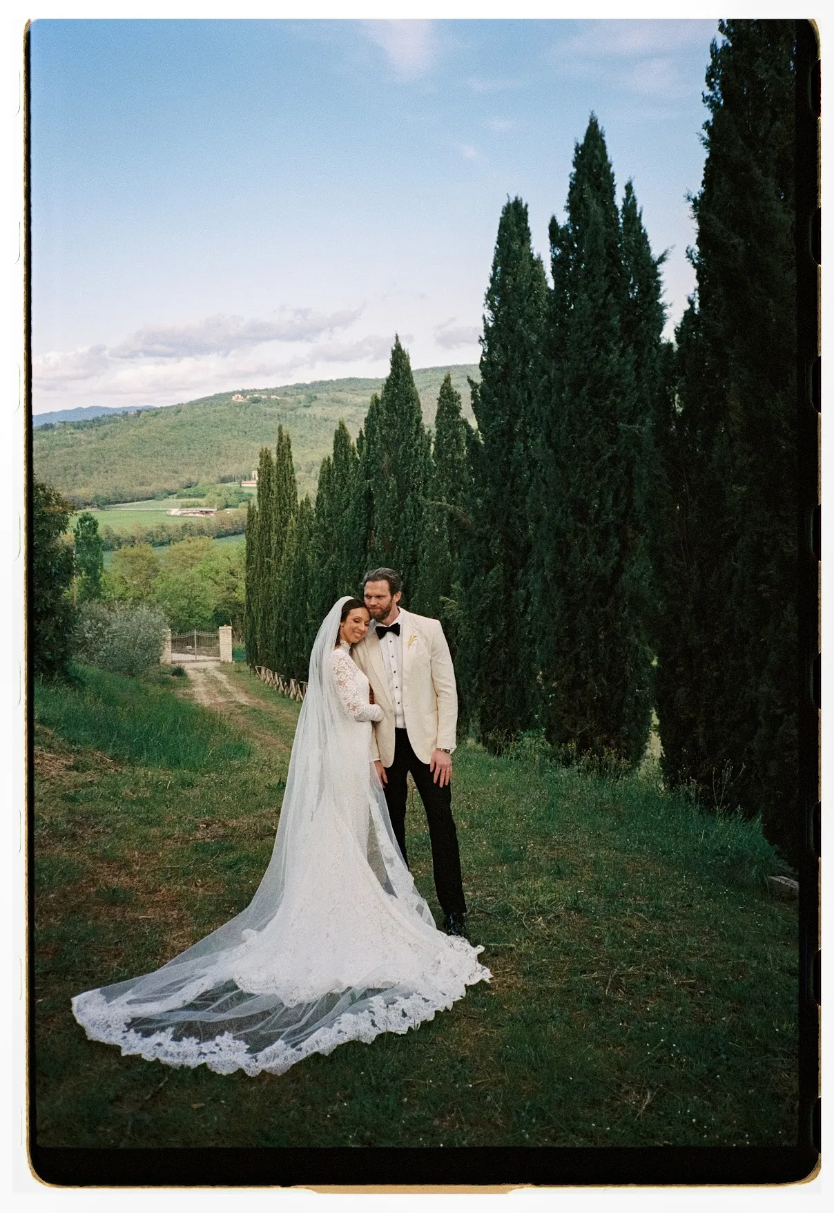 Groom carrying bride's train across the lawn at Villa Ada