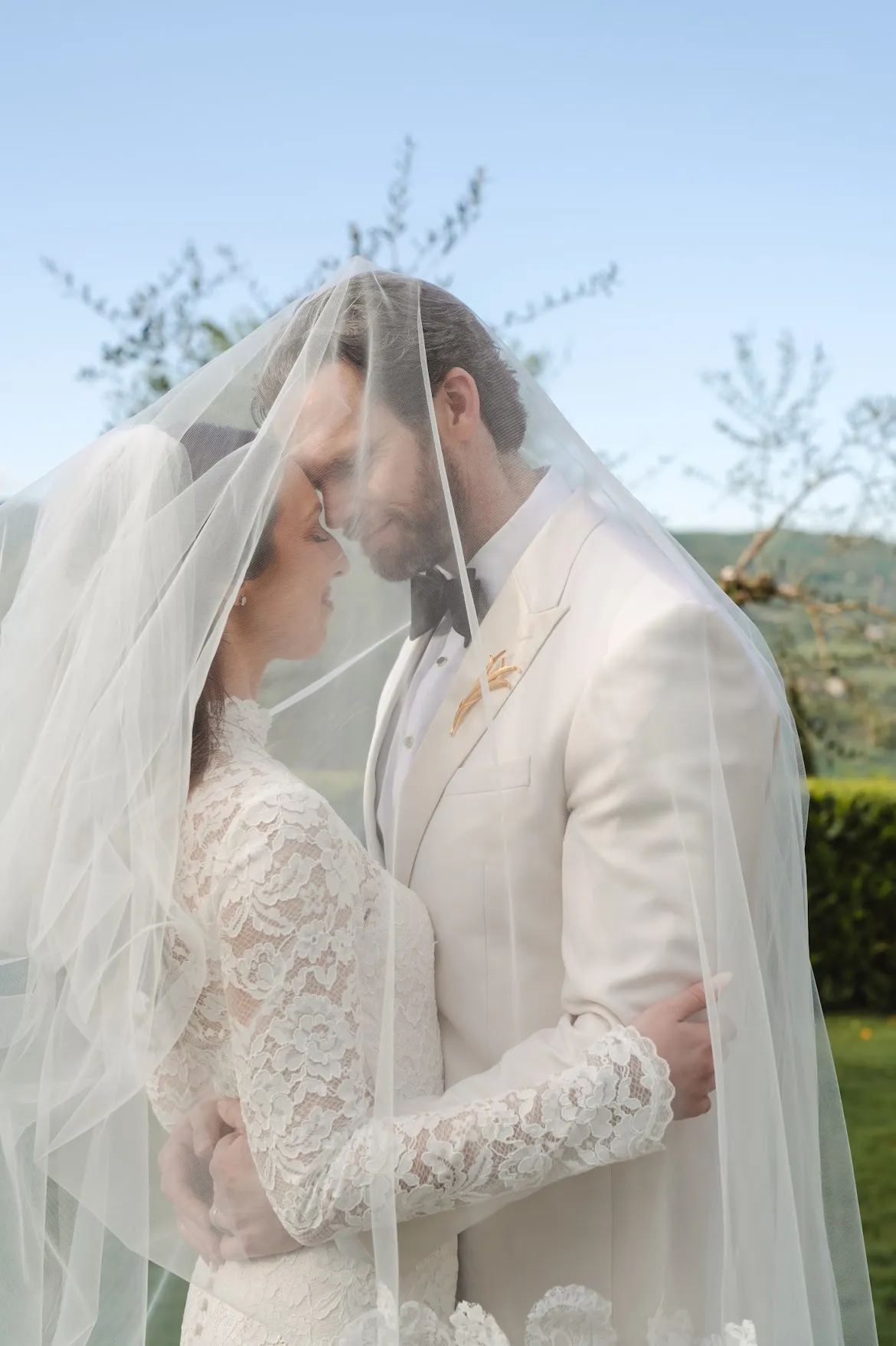 Newlyweds sharing a quiet moment among cypress and olive trees